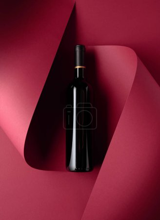 Photo for Bottle of red wine on a red background. Copy space for your text, top view. - Royalty Free Image