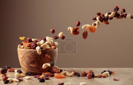 Foto de Flying dried fruits and nuts. The mix of nuts and raisins in a wooden bowl. Copy space. - Imagen libre de derechos