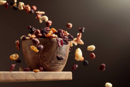 Foto de Frutos secos voladores y nueces. La mezcla de frutos secos y bayas secas están en un tazón de madera. - Imagen libre de derechos