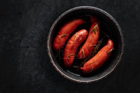 Téléchargez les photos : Saucisses bavaroises rôties au romarin sur une table en pierre noire. Espace de copie. - en image libre de droit
