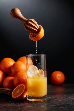 Photo for Orange juice is squeezed from fresh fruit. Juice is poured into a glass with ice. The concept of natural organic food. - Royalty Free Image