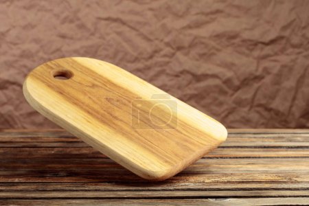Téléchargez les photos : Cutting board falling on an old wooden table. Food preparation. Culinary background. Empty wooden cutting board, product display space. - en image libre de droit