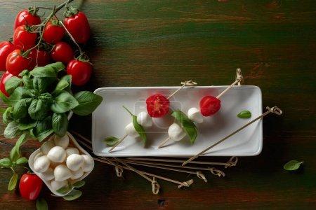 Téléchargez les photos : Mozzarella cheese with basil and tomatoes on a dark green wooden table. Top view. - en image libre de droit