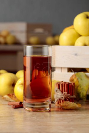 Foto de Las manzanas frescas jugosas en la caja de madera y el vaso del jugo de manzana en la mesa de la cocina. - Imagen libre de derechos