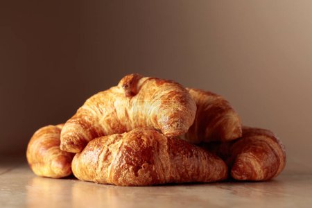 Photo for Freshly baked croissants on a beige ceramic table. Traditional French kitchen. - Royalty Free Image