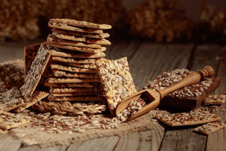 Foto de Crispy crackers with sunflower and flax seeds on an old wooden table. Simple healthy food. - Imagen libre de derechos