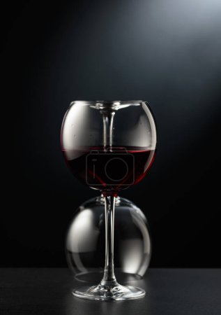 Foto de Vasos de vino tinto sobre fondo negro. Un vaso volcado está en el fondo. - Imagen libre de derechos