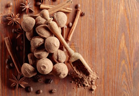Photo for Delicious chocolate truffles with cinnamon, anise, and coffee beans on a wooden table. Copy space. - Royalty Free Image
