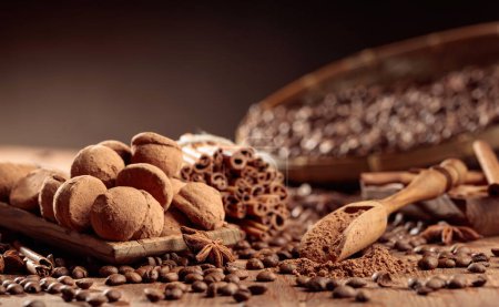 Photo for Chocolate truffles and a wooden spoon with cacao powder. Delicious chocolate truffles with cinnamon, anise, and coffee beans on a old wooden table. - Royalty Free Image