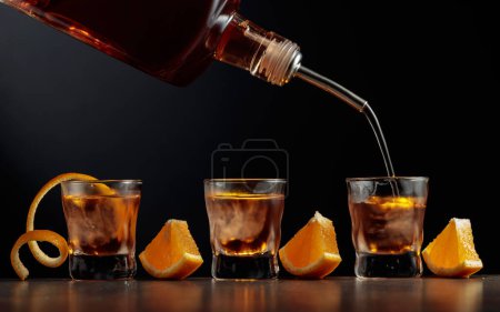 Foto de Cóctel a la antigua con hielo y naranja. Whisky se vierte en vasos con hielo. - Imagen libre de derechos