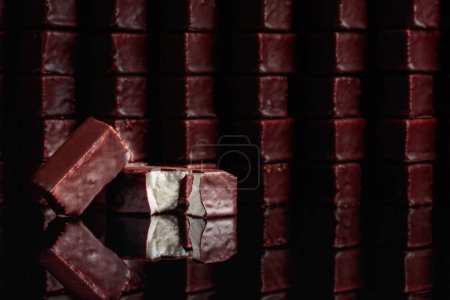 Téléchargez les photos : Bonbons au chocolat avec soufflé de lait sur fond noir réfléchissant. - en image libre de droit