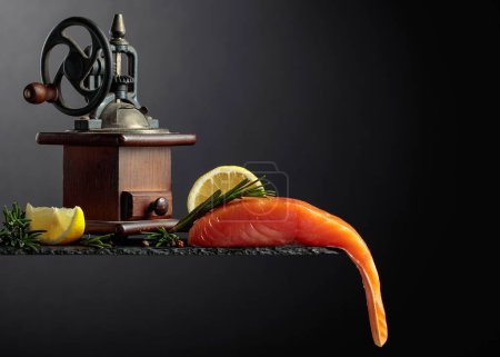 Téléchargez les photos : Salmon with rosemary, lemon, and peppercorn on a dark background. Copy space. - en image libre de droit