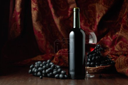 Téléchargez les photos : Nature morte avec vin rouge et raisins bleus sur une vieille table en bois. - en image libre de droit