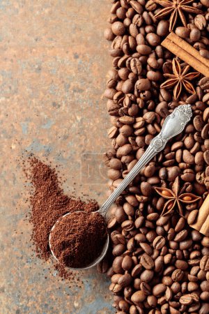 Photo for Ground coffee in a spoon and coffee beans with cinnamon and anise on a rusty metal background. Top view. Copy space. - Royalty Free Image
