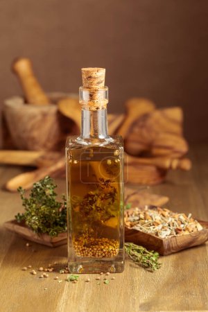Photo for Bottle of olive oil with thyme and spices. Olive oil and kitchen utensils on a wooden table. - Royalty Free Image
