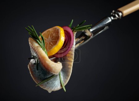 Téléchargez les photos : Filet de hareng à l'huile avec citron, oignon rouge et romarin sur fond noir. - en image libre de droit