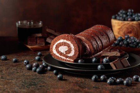 Photo for Chocolate roll cake with blueberries and a broken black chocolate bar. - Royalty Free Image