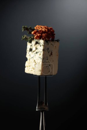 Photo for Blue cheese with walnuts and thyme on a fork. - Royalty Free Image
