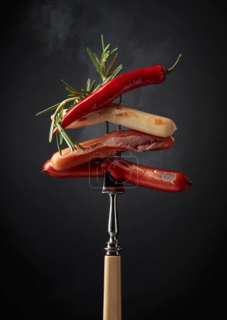 Photo for Various hot sausages with rosemary, and hot pepper on a fopk. - Royalty Free Image