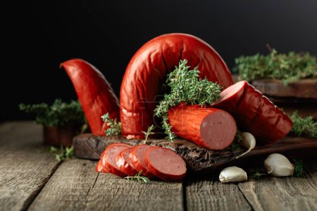 Foto de Smoked sausage with thyme and garlic on an old wooden table. - Imagen libre de derechos
