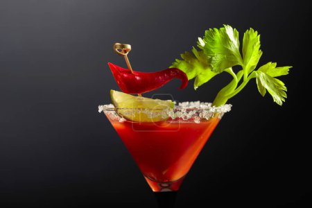 Foto de Cóctel Bloody Mary con apio, lima y pimienta roja. El vidrio está decorado con sal marina. - Imagen libre de derechos