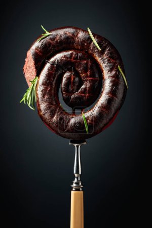 Téléchargez les photos : Pudding noir espagnol ou saucisse de sang avec romarin sur fond noir. - en image libre de droit
