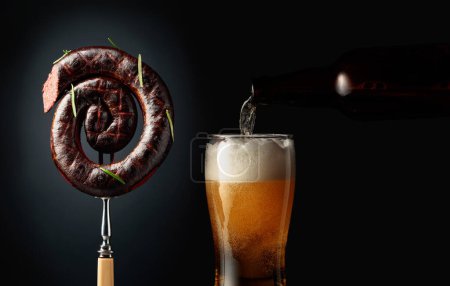 Photo for Black pudding or blood sausage with rosemary and a glass of beer. Copy space. - Royalty Free Image