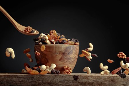 Photo for Flying dried fruits and nuts. The mix of dried nuts and raisins in a wooden bowl. Copy space. - Royalty Free Image