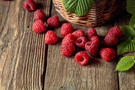 Photo for Ripe juicy raspberries with leaves on an old wooden table. - Royalty Free Image