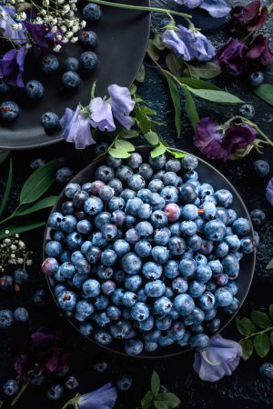 Photo for Summer still-life with blueberries, colored sweet peas, and meadow grasses on a dark blue background. Top view. - Royalty Free Image