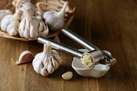 Téléchargez les photos : Garlic bulbs and garlic press on an old wooden table. - en image libre de droit