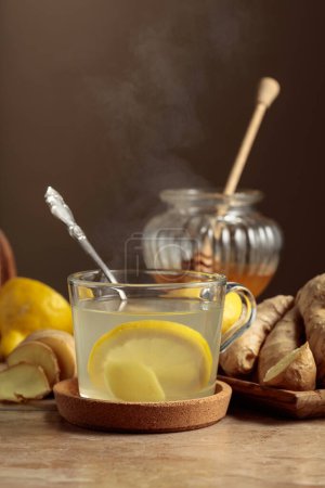 Foto de Té de jengibre con limón y miel en una mesa de cocina beige. - Imagen libre de derechos