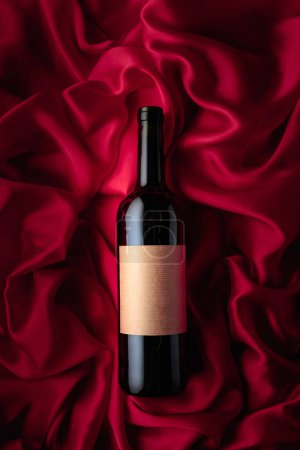 Photo for Bottle of red wine with an empty label on a satin background. Top view. - Royalty Free Image