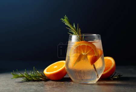 Téléchargez les photos : Cocktail gin tonic avec glace, romarin et orange sur une table en pierre. Espace de copie. - en image libre de droit