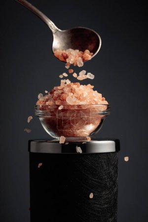 Foto de La sal rosa se vierte en un tazón de vidrio pequeño. - Imagen libre de derechos