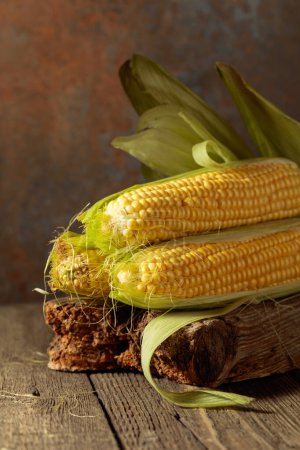 Foto de Fresh corn on cobs on a rustic wooden table. - Imagen libre de derechos