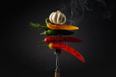 Photo for Red hot chili peppers with garlic and rosemary on black background. Concept of spicy food. - Royalty Free Image