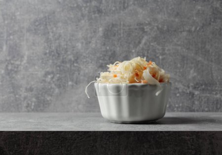 Photo for Bowl of sauerkraut with a carrot on a grey stone table. Copy space. - Royalty Free Image
