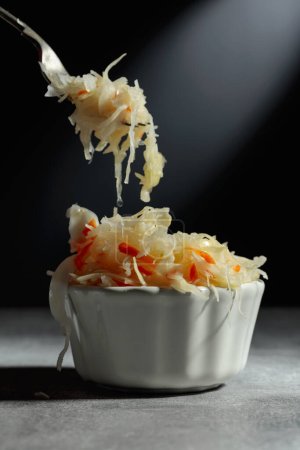 Téléchargez les photos : Bowl of sauerkraut with a carrot on a grey stone table. - en image libre de droit