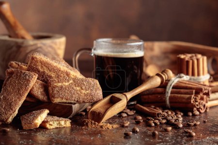 Foto de Galletas de canela dulce y una taza de café negro sobre un fondo vintage marrón. - Imagen libre de derechos