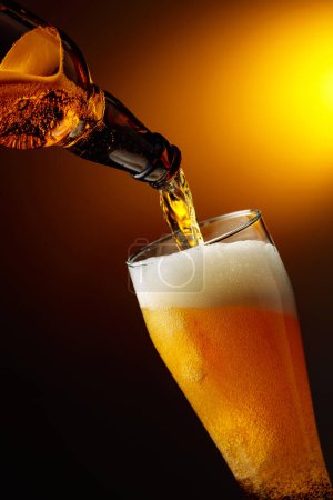 Téléchargez les photos : Verser la bière d'une bouteille dans un grand verre. - en image libre de droit