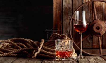 Photo for Crystal glass and snifter with rum, cognac, or whiskey on an old wooden background. Copy space. - Royalty Free Image