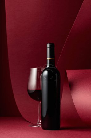 Photo for Bottle and glass of red wine on a red background. - Royalty Free Image