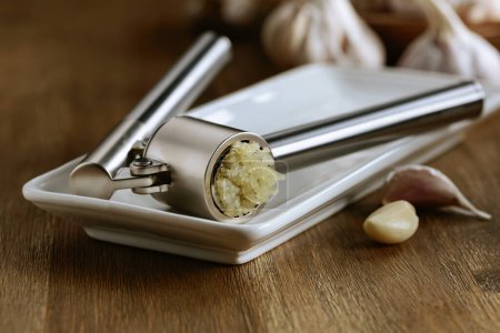 Photo for Garlic bulbs and garlic press on an old wooden table. - Royalty Free Image