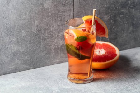 Photo for Cocktail with ice, mint, and grapefruit. A cold refreshing drink with ingredients on a grey background. Copy space. - Royalty Free Image