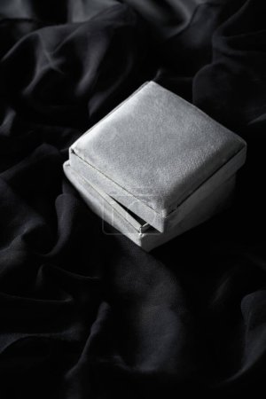 Foto de Caja de regalo gris sobre fondo satinado negro. - Imagen libre de derechos