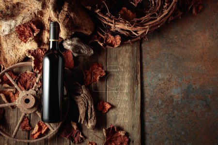 Téléchargez les photos : Bouteille de vin rouge sur fond rustique vintage avec vieux bois et feuilles de vigne séchées. Concept de vieux vin. Espace de copie. - en image libre de droit