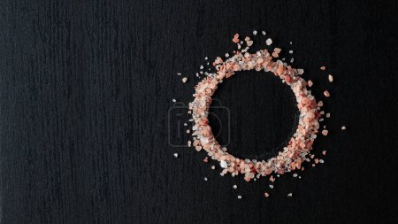 Photo for Pink Himalayan salt on a black ceramic table. Top view. Copy space. - Royalty Free Image