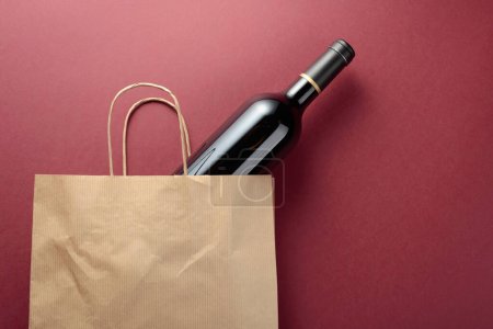 Foto de Bolsa de compras de papel reciclado con una botella de vino tinto. Vista superior, espacio de copia. - Imagen libre de derechos