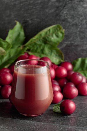 Téléchargez les photos : Red plums and a glass of plum juice on a black stone table. Copy space. - en image libre de droit